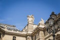 Architectural landscape of the roof and statues of the facade of the Louvre Museum in Paris from the place of pyramids Royalty Free Stock Photo