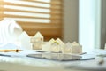 Architectural model of houses on desk with drawing tools and blueprints. Building, construction and architect concept