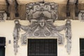 An architectural ornament relief above the building entrance door and under the terrace