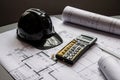 Architectural plans, helmet and calculator on the table. Architect workplace, Engineering and technician drawings and designs on