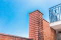 Architectural urban element of a column of red brick near the balcony against the blue sky