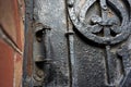 Architectural vintage background - old rusty black metal door with plates and aged metal door handle in the old red brick wall