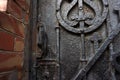 Architectural vintage background - old rusty black metal door with plates and aged metal door handle in the old red brick wall Royalty Free Stock Photo