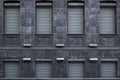 Architecture building fasade from grey granite stone with windows closed with metal rollets