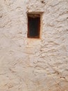 Small rusty window in old cement wall. Mud brick wall with window. Close-up of very old grungy weathered window. Architecture and Royalty Free Stock Photo