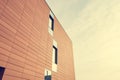 Architecture detail of modern building with orange facade and windows reflecting the sky. Royalty Free Stock Photo