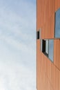 Architecture detail of modern building with orange facade and windows reflecting the sky. Royalty Free Stock Photo