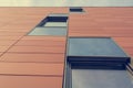 Architecture detail of modern building with orange facade and windows reflecting the sky. Royalty Free Stock Photo