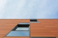 Architecture detail of modern building with orange facade and windows reflecting the sky. Royalty Free Stock Photo