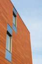 Architecture detail of modern building with orange facade and windows reflecting the sky. Royalty Free Stock Photo