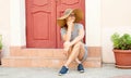Woman sitting on strairs next to the bright red door Royalty Free Stock Photo