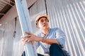 Architecture man sitting on the ground and hold blueprints design plan and wearing safety helmet at site construction in hot Royalty Free Stock Photo