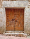Old-fashioned brown wooden outside door with two metal knockers and a lock in an old stone wall. Architecture and medieval Royalty Free Stock Photo