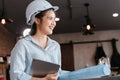 Architecture woman hold blueprints design plan and wearing safety helmet in room at site construction. Architecture, engineering, Royalty Free Stock Photo