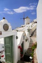 Architecturel building in Santorini with the door open and view to the beautiful buildings and a mill with a blue sky