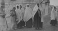 Archival monochrome photo showing a group of Arab women in traditional dress, taken in the City of Hebron, Palestine in 1920.