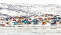 Arctic city center panorama with colorful Inuit houses on the rocky hills covered in snow with snow and mountain in the background Royalty Free Stock Photo