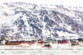 Arctic city panorama with colorful Inuit cottages and oil factory on the rocky hills covered in snow and mountain in the