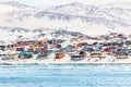 Arctic city panorama with colorful Inuit houses on the rocky hills covered in snow with snow and mountain in Royalty Free Stock Photo