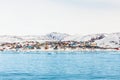 Arctic city panorama with colorful Inuit houses on the rocky hills covered in snow with snow and mountain in Royalty Free Stock Photo