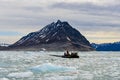 People on inflatable boat in Arctic sea with ice in Svalbard