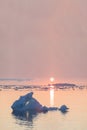 Arctic nature landscape with icebergs in Greenland icefjord with midnight sun sunset / sunrise in the horizon.  Early morning Royalty Free Stock Photo