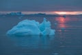 Arctic nature landscape with icebergs in Greenland icefjord with midnight sun sunset / sunrise in the horizon. Early morning