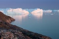 Arctic nature landscape with icebergs in Greenland icefjord with midnight sun sunset / sunrise in the horizon.  Early morning Royalty Free Stock Photo