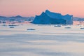 Arctic nature landscape with icebergs in Greenland icefjord with midnight sun sunset / sunrise in the horizon. Early morning