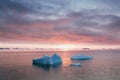 Arctic nature landscape with icebergs in Greenland icefjord with midnight sun sunset / sunrise in the horizon. Early morning