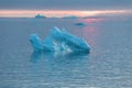 Arctic nature landscape with icebergs in Greenland icefjord with midnight sun sunset / sunrise in the horizon. Early morning