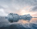 Arctic nature landscape with icebergs in Greenland icefjord with midnight sun sunset sunrise in the horizon. Early