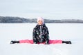 Arctic outdoor winter portrait of a young child girl in winter clothing sitting in split in the snow against frozen landscape back Royalty Free Stock Photo