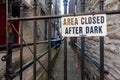 Area Closed After Dark sign on metal plate is attached to the metal railings of a door