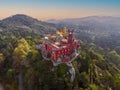 Areal drone shot of Pena Palace at sunset golden hour: majestic castle with several turret towers