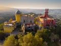 Areal drone shot of Pena Palace at sunset golden hour: majestic castle with several turret towers