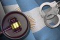 Argentina flag with judge mallet and handcuffs in dark room. Concept of criminal and punishment, background for