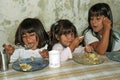 Poor hungry Argentinian girls eat in a soup kitchen