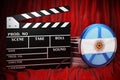 Argentinean cinematography, film industry, cinema in Argentina. Clapperboard with and film reels on the red fabric, 3D rendering