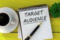 ARGET AUDIENCE - words on a white sheet on a yellow wooden background with a pen and a cup of coffee