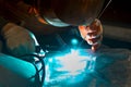 Argon-arc welding welder at the workplace welds the part