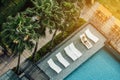 Arial view of tourist lay down on outdoor chairs near swimming pool with palm trees in hotel area Royalty Free Stock Photo