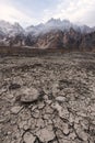 Arid climate, dry cracked drought field with Passu Cathedral mountain landscape in Pakistan