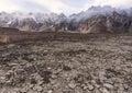 Arid climate, dry cracked drought field with Passu Cathedral mountain landscape in Pakistan