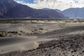 Arid dry dessert sand dunes of nubra valley with himalayan barren mountain range in the background at ladakh, Kashmir, india Royalty Free Stock Photo