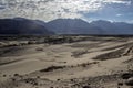 Arid dry dessert sand dunes of nubra valley with himalayan barren mountain range in the background at ladakh, Kashmir, india Royalty Free Stock Photo