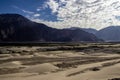 Arid dry dessert sand dunes of nubra valley with himalayan barren mountain range in the background at ladakh, Kashmir, india Royalty Free Stock Photo