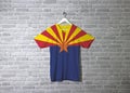 Arizona flag on shirt and hanging on the wall with brick pattern wallpaper. The states of America Royalty Free Stock Photo