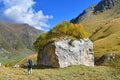 Arkhyz, Russia, Caucasus, September, 23, 2018. Tourist passes by large stone with birches growing on it in the valley of the rive Royalty Free Stock Photo