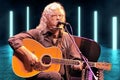 Arlo Guthrie, Woodstock Alum with acoustic guitar and microphone